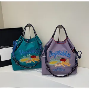 Détail du sac cabas en nylon avec broderie de légumes colorés et anses tissées bicolores