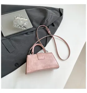Detail of pink pebbled leather hourglass handbag with top handle and adjustable strap