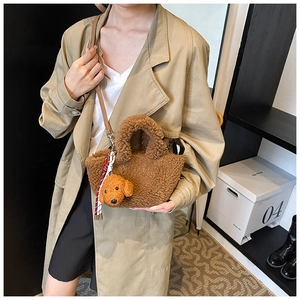 Detail of plush brown bucket bag with dog pendant and checkered scarf on model