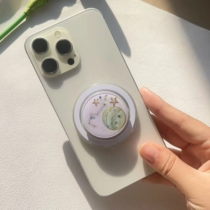 Handy-Grip mit Sternenhimmel-Muster und Glitzer auf einem weißen Smartphone montiert