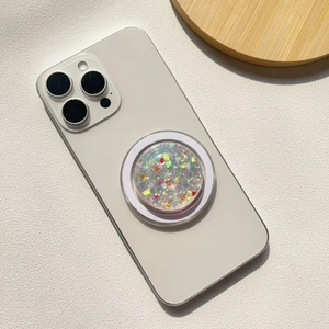Detail of round glitter phone socket with heart sequins on a white smartphone