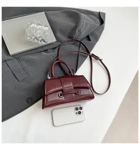 Detail of burgundy hourglass handbag with pleated texture and adjustable shoulder strap