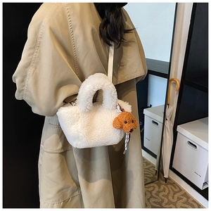 Rear view of a white plush bucket bag with a brown poodle pendant on a model