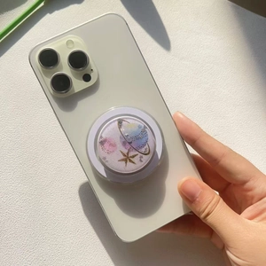Nahaufnahme einer glitzernden lila Planeten-Handyhalterung mit Goldsternen auf Smartphone