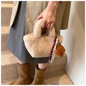 Beige faux fur bucket bag shown with a cute bear charm in a stylish winter street setting
