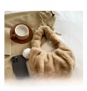 Detail of light camel plush dumpling bag with white fur ball and gold chain strap