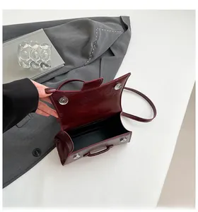 Detail of burgundy hourglass handbag with crocodile texture and magnetic closure
