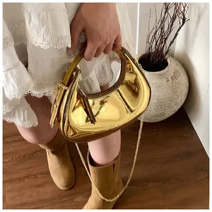 Detail of metallic gold crescent bag with mirror finish and slim metal chain