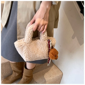 Close-up of beige plush bucket bag with cute bear charm and woven rope decoration