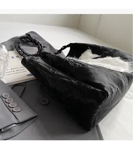 Close-up of black pleated tote bag with white faux fur trim and braided rope handles