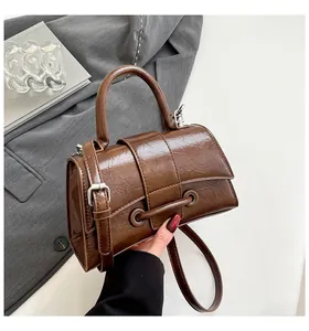 Detail of dark brown hourglass handbag with crinkled patent leather and silver buckle strap