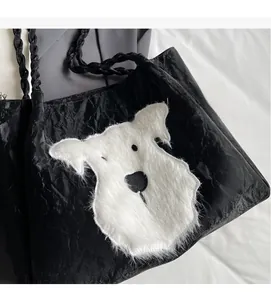 Detail of black pleated tote bag featuring a white faux fur puppy patch and rope handles