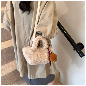 Model wearing a fuzzy cream plush bucket bag with a cute bear charm on a staircase