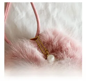 Detail of pink faux fur keychain with gold bead chain and pearl accent with diamond ring