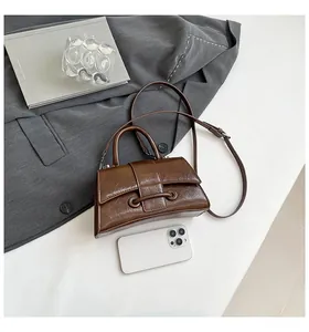 Close-up of deep brown hourglass handbag with vintage pleated texture on a grey suit background