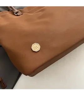 Close-up of deep brown nylon tote with premium gold metal logo and durable stitching