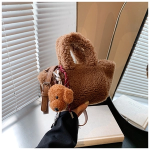 Detail of plush brown teddy bucket bag with cute bear charm and adjustable shoulder strap