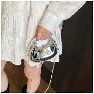 Detailed shot of silver mini crescent bag featuring metallic patent finish and gold chain strap