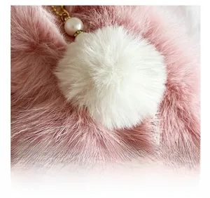 Macro detail of white faux fur pompom with elegant pearl and gold hardware accents