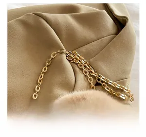 Detailed close-up of the elegant golden metal chain strap on the khaki plush handbag
