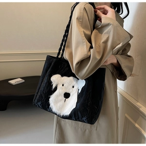 Detailed side view of a large black crinkled tote bag with white plush puppy embroidery