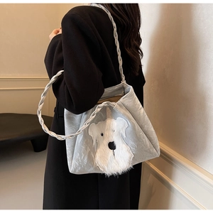 Detail of silver metallic tote bag with plush puppy patch shown on a model shoulder