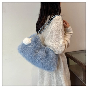 Detail of light blue faux fur tote bag with fluffy pompom charm and soft plush texture