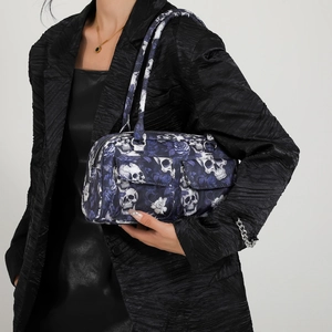 Floral skull print shoulder bag with dual zipper and front pockets shown on model