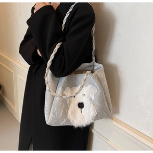 Detail of silver tote bag featuring schnauzer patch and woven shoulder strap on model