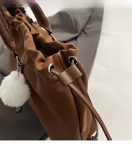 Close-up of brown nylon tote bag with drawstring, silver metal rings and plush charm