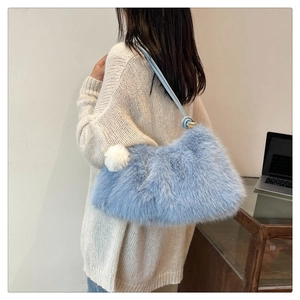 Detail of light blue faux fur shoulder bag with soft texture and white pompom charm