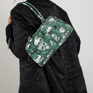 Green gothic skull and flower print shoulder bag shown on model in black coat