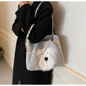 Detail of silver pleated tote bag with plush schnauzer embroidery and woven strap