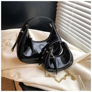 Detail of two-piece black patent leather crescent bags with gold hardware on tweed