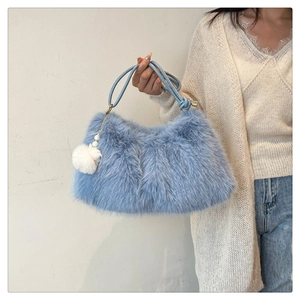Detail of light blue faux fur tote bag with a white pompom and pearl charm decoration