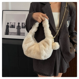 Detail of soft cream faux fur dumpling bag with gold chain and pearl charm accessory