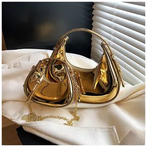 Detail showing two gold mirror patent leather crescent bags with metal chain straps