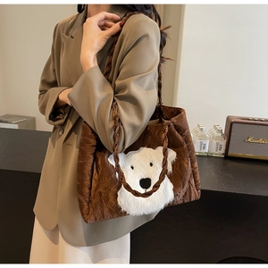 Detail of a brown tote bag featuring a plush white animal patch and woven shoulder strap