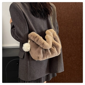 Detail of khaki plush cloud bag with gold chain strap and cute white pompom on model