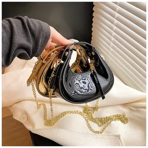 Macro detail of mini crescent chain bags in shiny black and golden mirror finishes