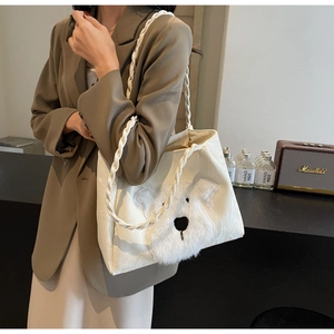 Detail showing plush white dog motif and braided shoulder strap on a white tote bag
