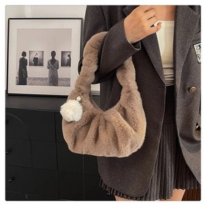 Close-up of brown plush dumpling bag with soft textures and a white pom-pom charm detail