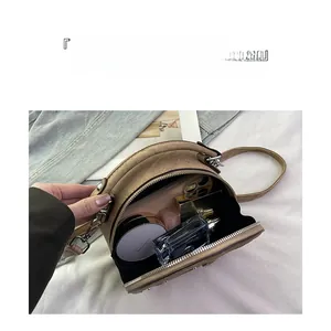 Interior view of small round crossbody bag showing storage for phone and cosmetics