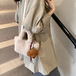 Fashion minimalist plush cream bucket bag with teddy dog charm on a khaki trench coat