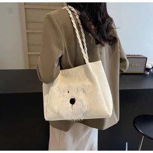 Detail of white tote bag featuring a cute plush dog patch and woven shoulder strap