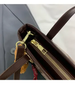 Detail of dark brown leather tote featuring high-quality gold zipper and metallic hardware