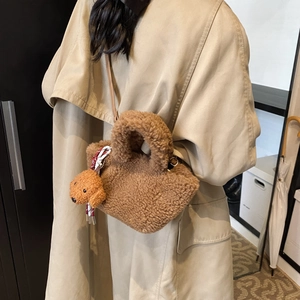 Brown teddy plush bucket bag with cute puppy charm worn crossbody on a beige coat