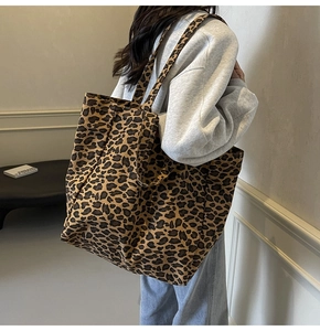 Detailed view of large leopard print canvas tote bag worn by a model on shoulder
