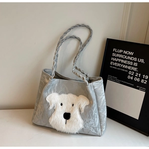 Detail of silver tote bag featuring a plush puppy patch and braided handle textures