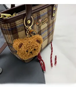 Detail of plaid tote bag with brown bear pendant and cartoon embroidery on the side
